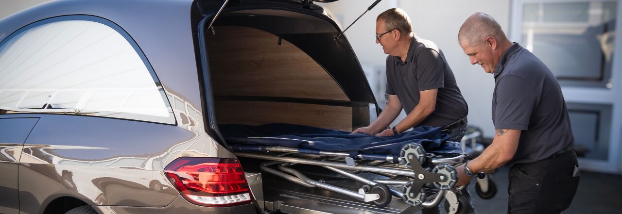 Ausladung der Trage aus dem Bestattungswagen